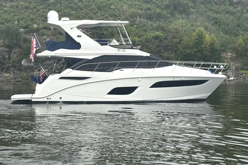 Smooth Yacht Photos Pics 2018 Sea Ray Fly 460 yacht on calm water, surrounded by lush greenery.