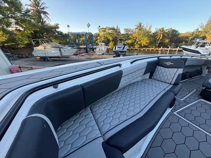  Yacht Photos Pics 2022 Fountain 38 SC boat interior with hexagonal-patterned seating, docked near other boats.