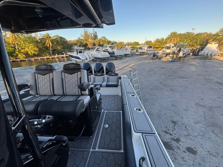  Yacht Photos Pics 2022 Fountain 38 SC boat interior with seating, docked near other boats.