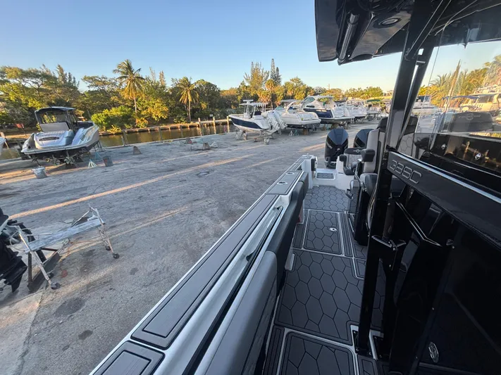  Yacht Photos Pics 2022 Fountain 38 SC boat docked, surrounded by other boats and lush greenery.