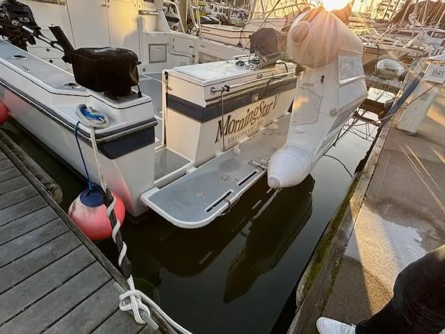 Morning Star V Yacht Photos Pics 1997 Albin 31 Tournament boat docked, rear view with outboard motor and sunset reflection.