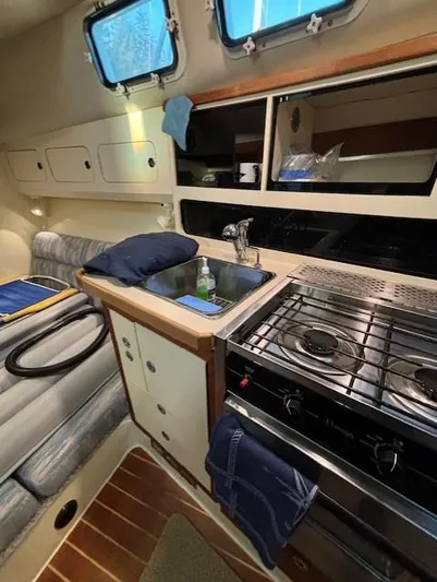 Morning Star V Yacht Photos Pics 1997 Albin 31 Tournament boat interior with kitchen, stove, and seating area.