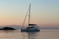 2018 Leopard 45 catamaran sailing at sunset near rocky island.
