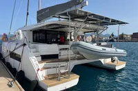 2018 Leopard 45 catamaran docked with dinghy, showcasing spacious deck and modern design.