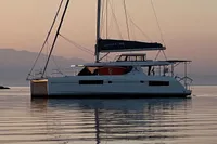 2018 Leopard 45 catamaran sailing at sunset on calm waters.