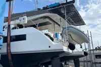 2018 Leopard 45 catamaran with solar panels and dinghy, docked under a blue sky.
