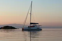 2018 Leopard 45 catamaran sailing at sunset near a small island.