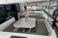 Spacious deck of 2018 Leopard 45 yacht with seating and table, docked at marina.