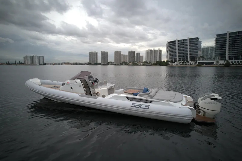  Yacht Photos Pics 2014 SACS Strider 13 boat on calm water with cityscape background.