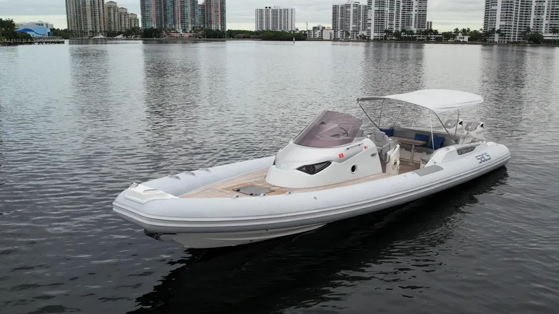  Yacht Photos Pics 2014 SACS Strider 13 boat on calm water with city skyline in the background.