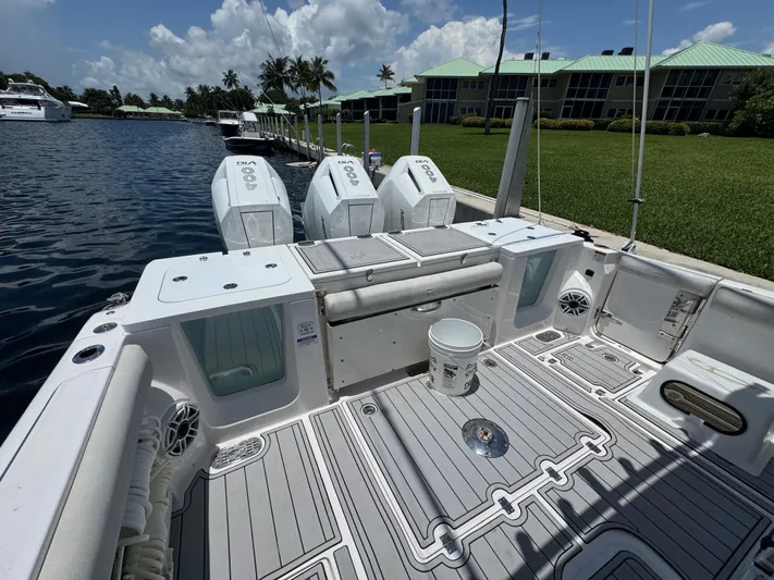  Yacht Photos Pics 2023 Sea Fox 368 Commander boat deck with triple outboard engines, docked by waterfront homes.