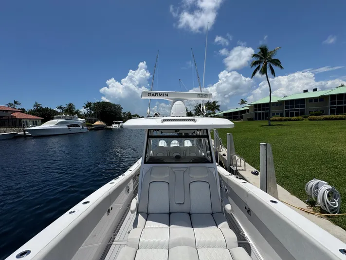  Yacht Photos Pics 2023 Sea Fox 368 Commander boat docked by waterfront homes under a clear blue sky.