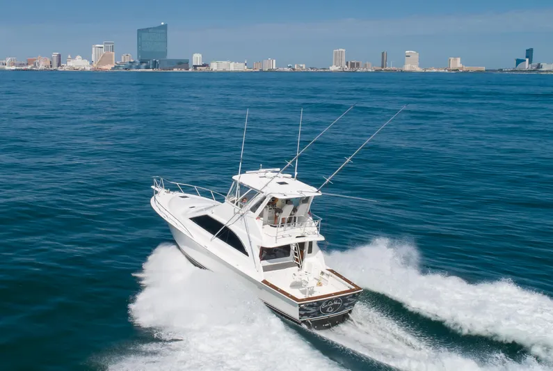 East Coast Hooked Yacht Photos Pics 1999 Ocean Yachts 48 Super Sport cruising on open water with city skyline in background.