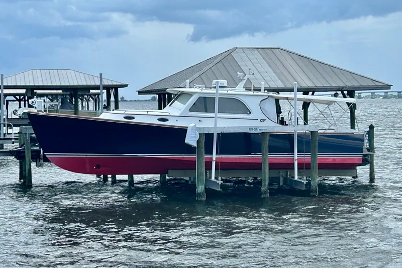 Clarity Yacht Photos Pics 2006 Hinckley 36 EP Picnic Boat docked on a lift under a covered structure.