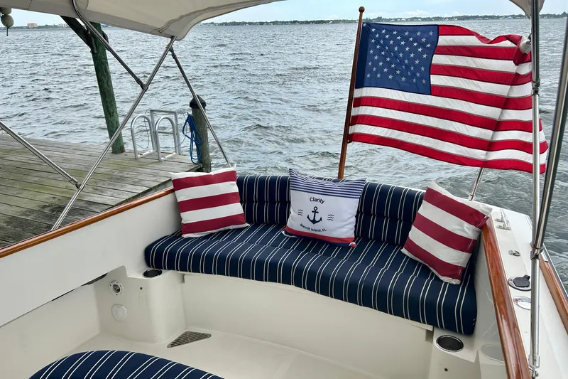 Clarity Yacht Photos Pics 2006 Hinckley 36 EP Picnic Boat with American flag and striped seating by the water.