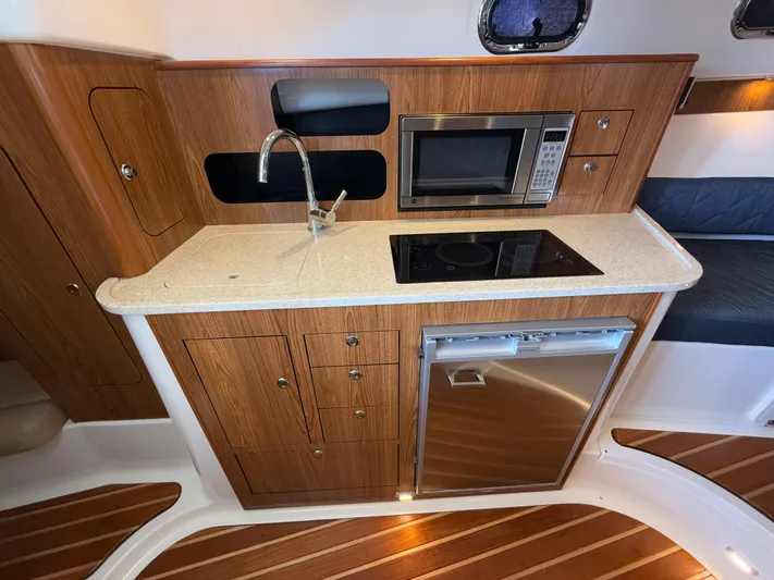  Yacht Photos Pics 2011 Pursuit OS 345 Offshore galley with wood cabinetry, sink, microwave, and cooktop.