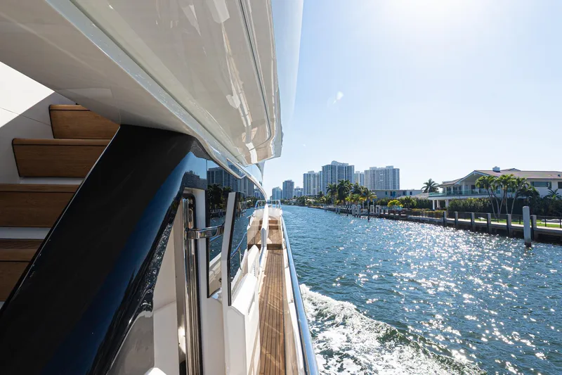  Yacht Photos Pics Luxurious 2022 Princess Y85 yacht cruising along a sunny waterfront cityscape.