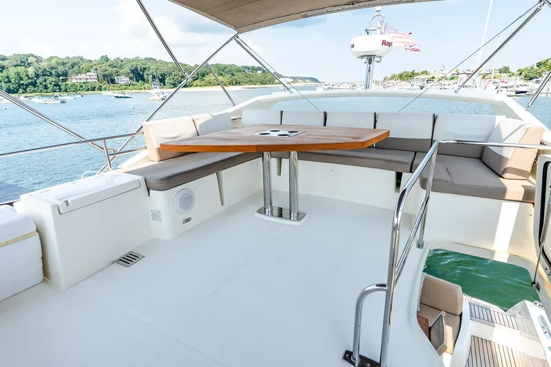 Passion Play Yacht Photos Pics Flybridge of 2014 Prestige Yachts 550, featuring spacious seating and a wooden table.