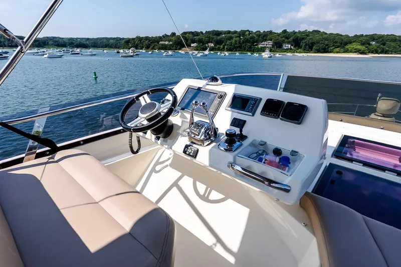 Passion Play Yacht Photos Pics Flybridge helm of 2014 Prestige Yachts 550, overlooking serene waters and distant boats.
