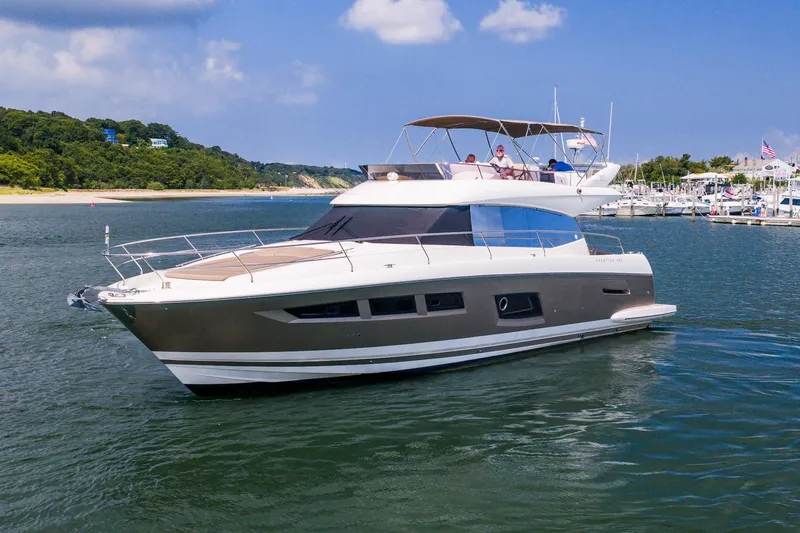 Passion Play Yacht Photos Pics 2014 Prestige Yachts 550 Flybridge cruising near a marina under a clear blue sky.