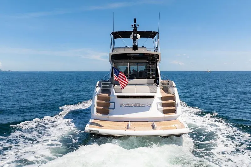  Yacht Photos Pics 2023 Sunseeker 65 Sport Yacht cruising on open sea, rear view with American flag.