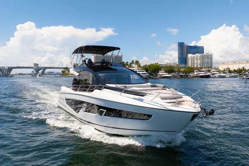  Yacht Photos Pics 2023 Sunseeker 65 Sport Yacht cruising on a sunny day near a cityscape.