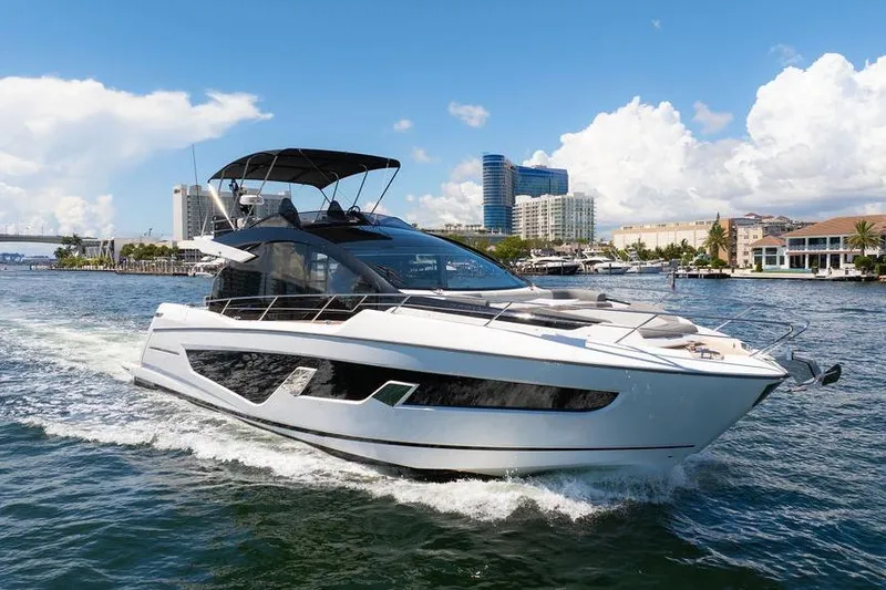  Yacht Photos Pics 2023 Sunseeker 65 Sport Yacht cruising on a sunny day near urban waterfront.