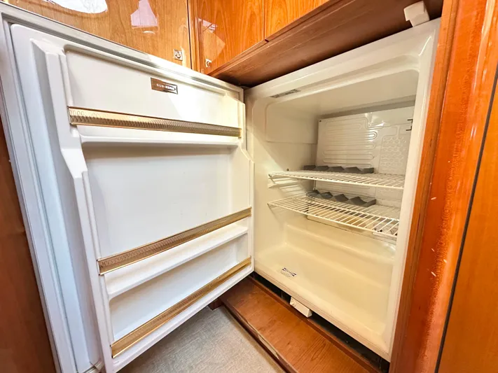 Lai Lani Yacht Photos Pics Open refrigerator inside 2005 Sunseeker Manhattan 66 yacht, featuring wooden cabinetry and empty shelves.