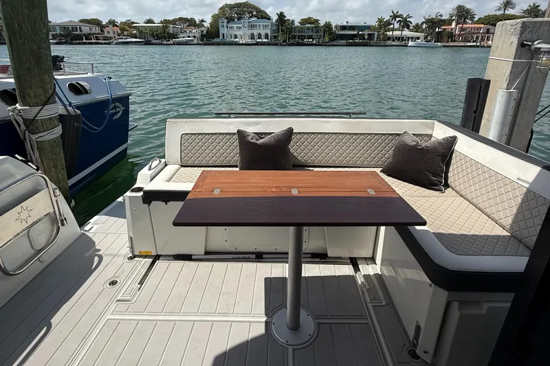  Yacht Photos Pics Jeanneau NC 37 boat deck with seating and table, overlooking waterfront homes.