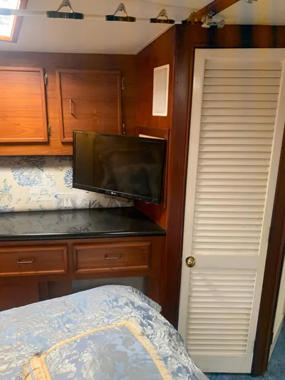Lolly Yacht Photos Pics 1985 Ocean Yachts 55 Super Sport bedroom with TV, wooden cabinets, and floral bedding.