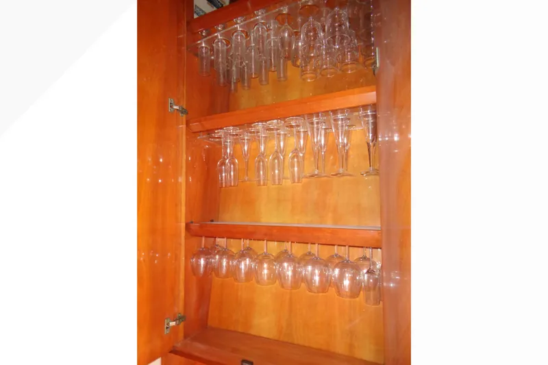 (project Boat) 1995 Azimut 78ultra @ixtapa-mexico Yacht Photos Pics Wine glass cabinet on 1995 Azimut 78 Ultra Motoryacht, featuring wooden shelves and glassware.