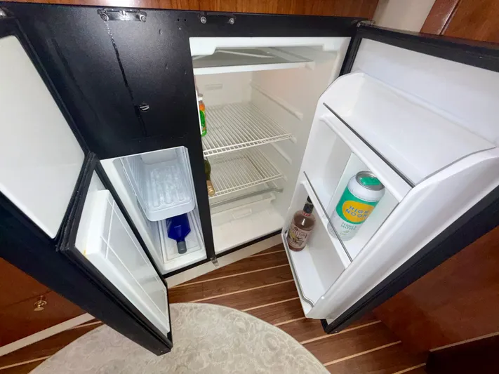  Yacht Photos Pics Open refrigerator inside 2009 Cruisers Yachts 420 Coupe, showing beverages and wooden flooring.