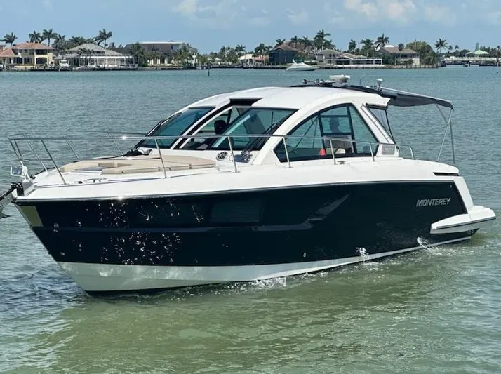  Yacht Photos Pics 2016 Monterey 360 Sport Coupe cruising on calm waters near a coastal neighborhood.
