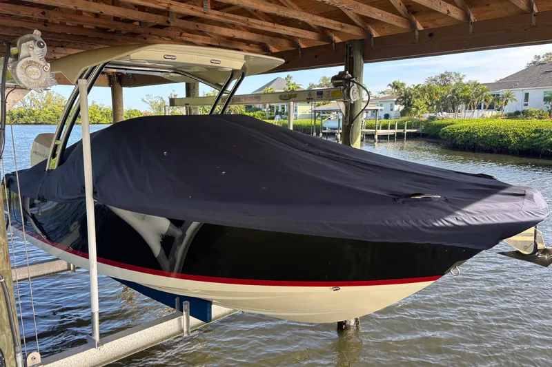  Yacht Photos Pics 2023 Chris-Craft Calypso 24 boat covered and docked under a wooden shelter.