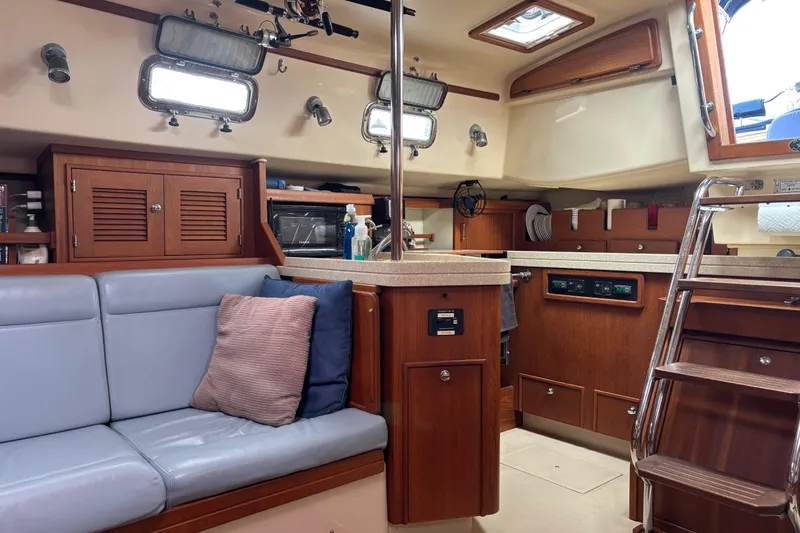 Moondance Yacht Photos Pics Interior of a 2007 Island Packet 370 sailboat, featuring a cozy seating area and wooden cabinetry.