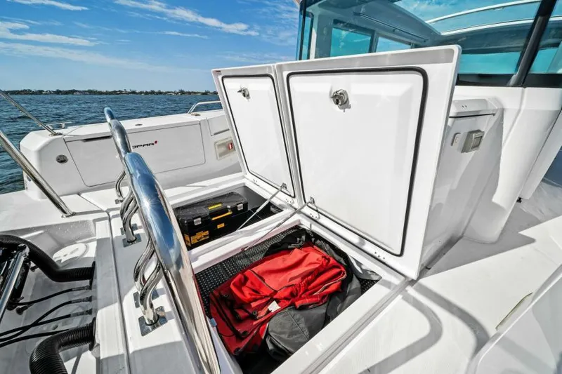  Yacht Photos Pics 2022 Axopar 37 Cross Cabin storage compartment with red bag, open on a sunny day.