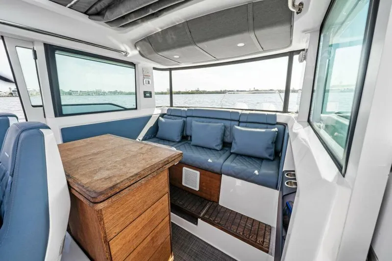  Yacht Photos Pics Interior of 2022 Axopar 37 Cross Cabin with blue seating and wooden table.