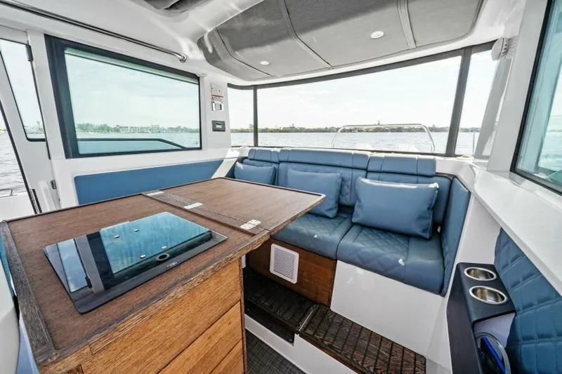  Yacht Photos Pics Interior of 2022 Axopar 37 Cross Cabin with blue seating and wooden table.