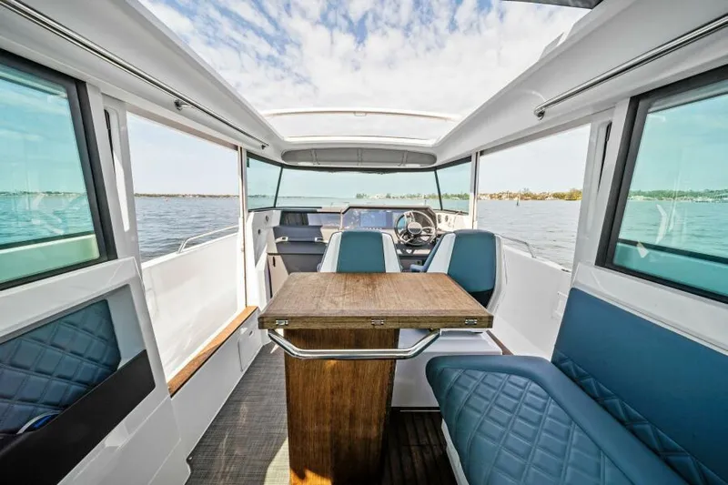  Yacht Photos Pics Interior of 2022 Axopar 37 Cross Cabin with seating and table, overlooking water.