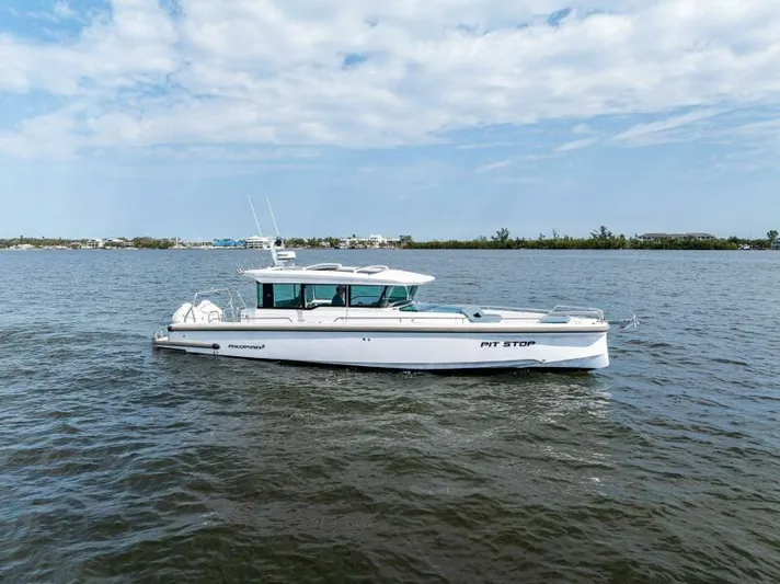  Yacht Photos Pics 2022 Axopar 37 Cross Cabin boat on calm water under a partly cloudy sky.