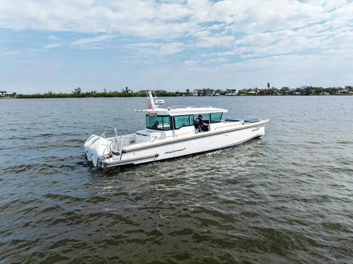  Yacht Photos Pics Axopar 37 Cross Cabin 2022 cruising on a calm lake under a partly cloudy sky.