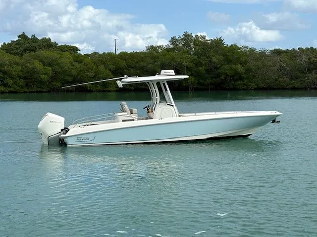  Yacht Photos Pics 2022 Boston Whaler DAUNTLESS boat on calm water with lush green trees in the background.