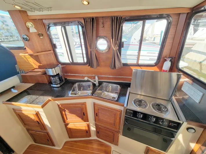  Yacht Photos Pics 2011 Ranger Tugs R-29 interior kitchen with stove, sink, and wooden cabinetry.