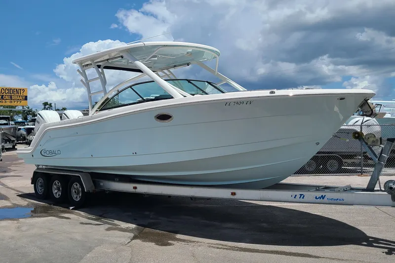  Yacht Photos Pics 2024 Robalo R317 Dual Console boat on trailer under cloudy sky.
