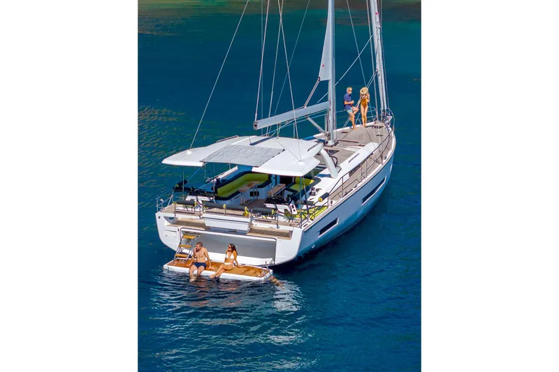  Yacht Photos Pics Luxury Hanse 590 yacht, 2026 model, with people relaxing on deck in serene waters.