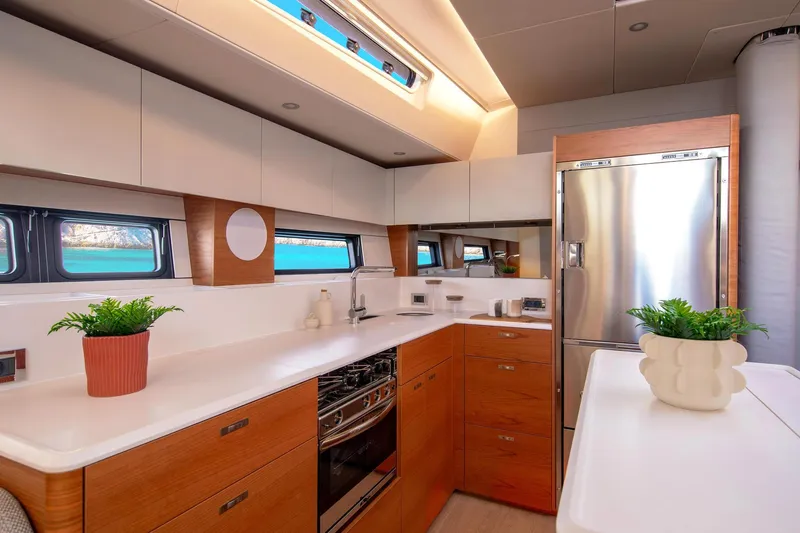  Yacht Photos Pics Luxurious 2026 Hanse 590 yacht kitchen with modern design, stainless steel appliances, and elegant wood cabinetry.