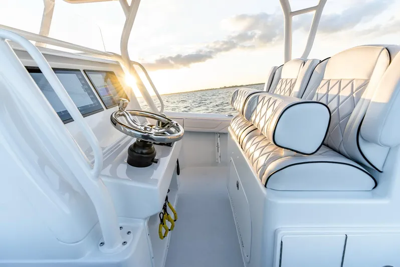  Yacht Photos Pics 2023 Yellowfin 34 boat interior with steering wheel and cushioned seating at sunset.