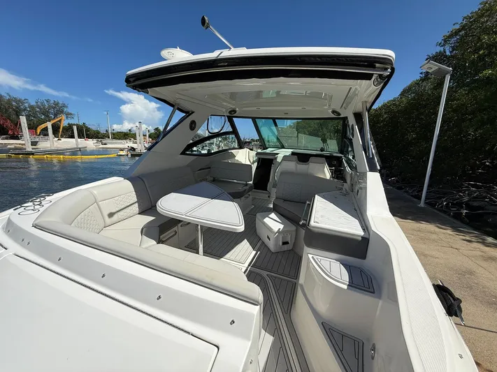  Yacht Photos Pics 2022 Sea Ray Sundancer 320 Outboard boat interior with seating and table, docked by the water.