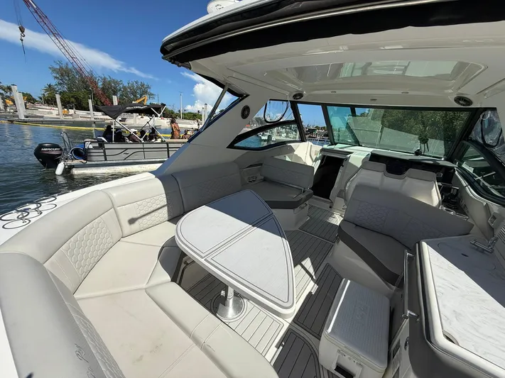  Yacht Photos Pics 2022 Sea Ray Sundancer 320 Outboard interior with luxurious seating and table, docked by the water.