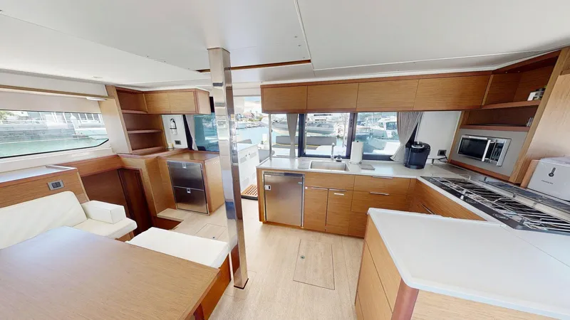 Sliver Fern Yacht Photos Pics Modern kitchen interior of 2020 Lagoon 46 yacht with wood cabinetry and appliances.